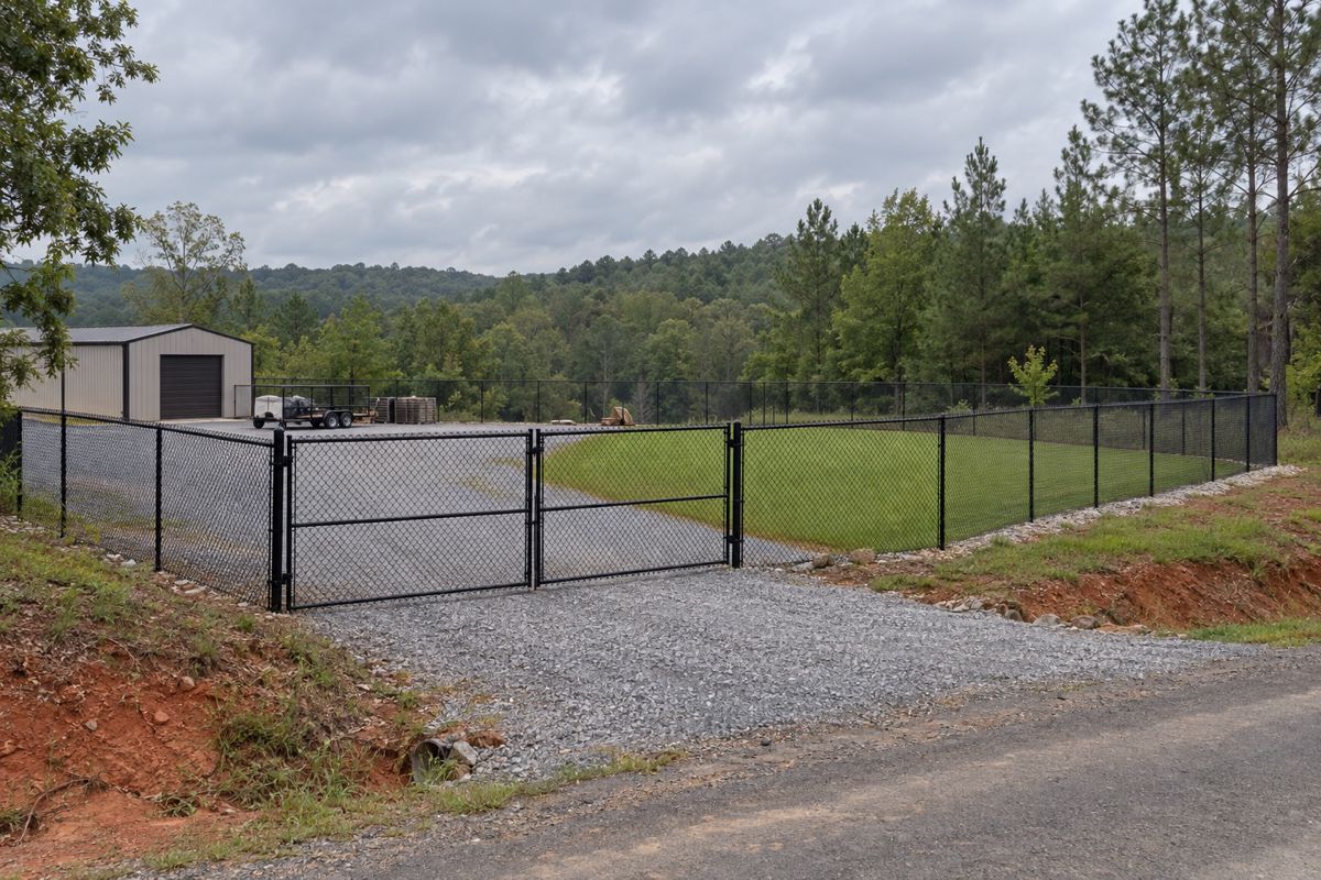 Black chain link fence and drive gate on rolling Alabama land